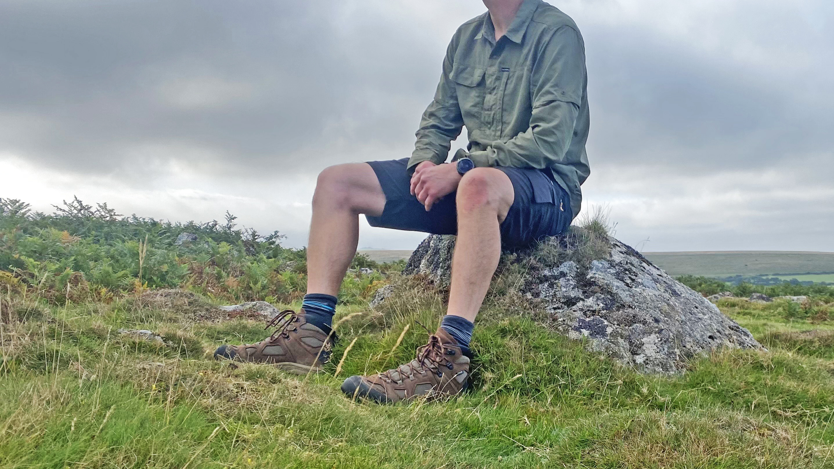 A walker sat on a rock, wearing the Columbia Skien Valley shirt, with the sleeves down
