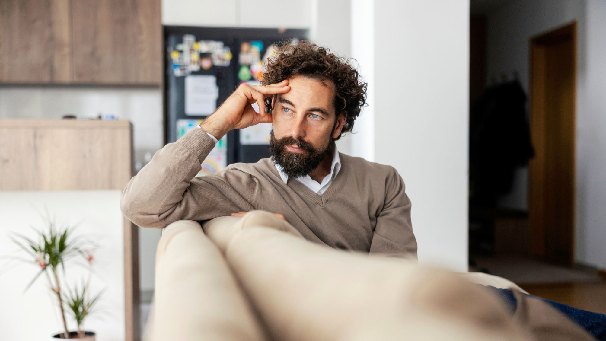 A man sitting on a couch thinking about money. 