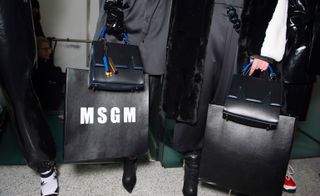 A close-up of an 'MSGM' text black leather bag