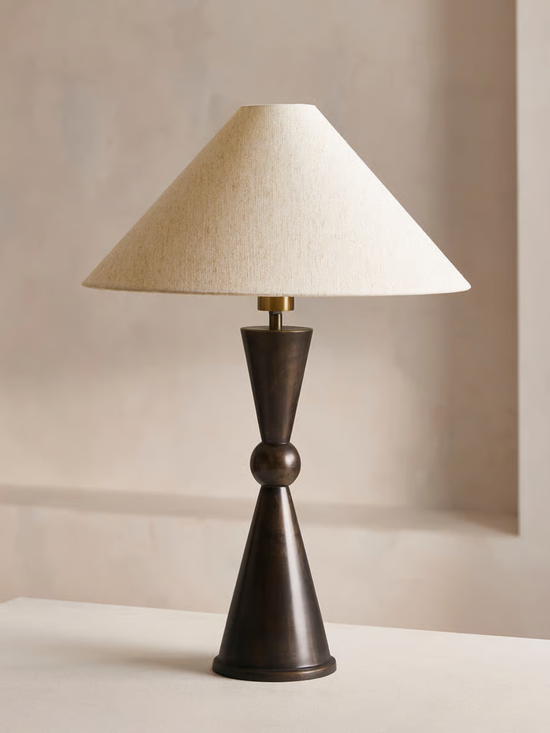 A brassy table lamp with white linen from Soho Home