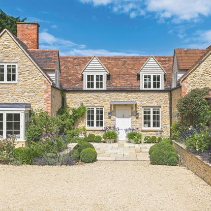 Gravel driveway of stone cottage home with dormer windows