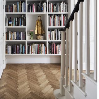 Hallway with wooden chevron flooring and a built in bookcase.
