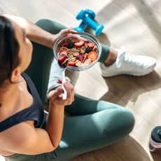 A woman eating cottage cheese, cereal and fruit at home