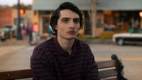 Mike sitting on a bench in Stranger Things.