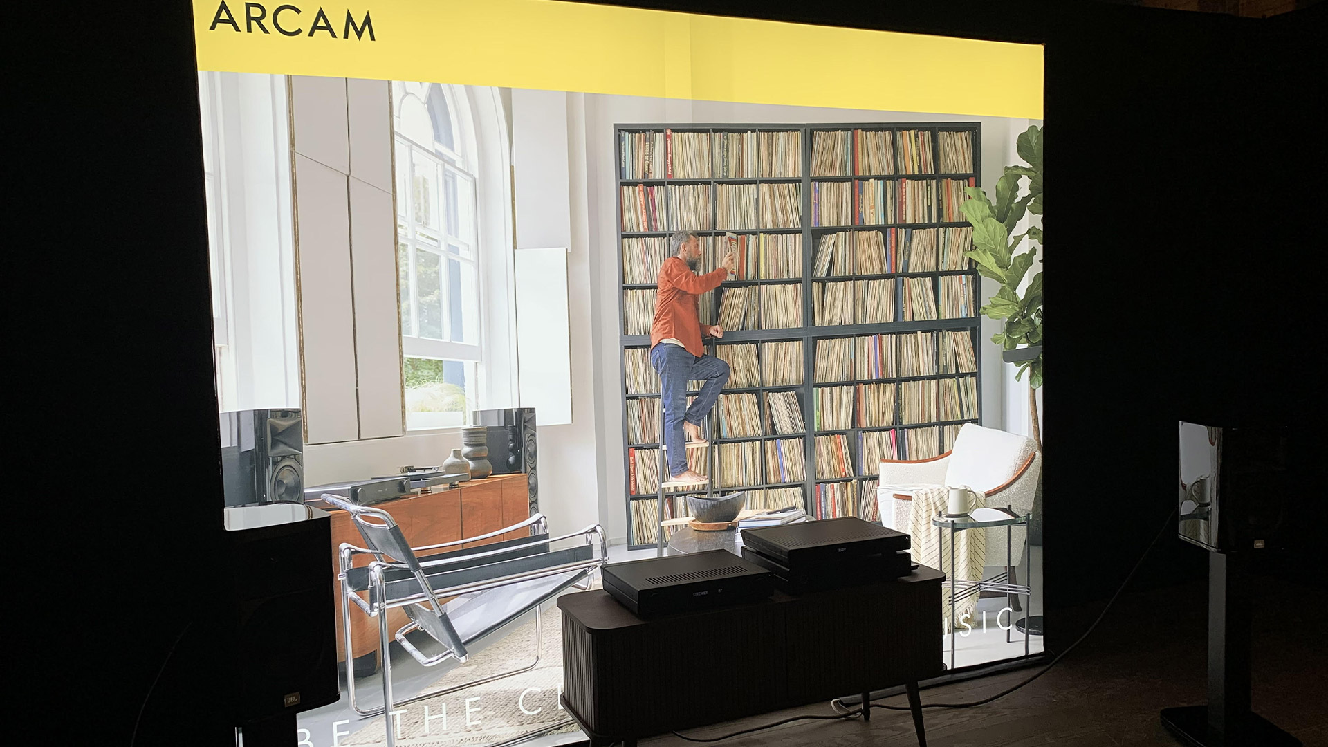 Two speakers stand on either side of an amplifier.