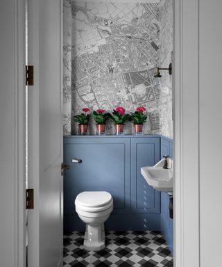 A bathroom with a WC and a built-in cistern cover that features a mantel shelf with pink flowers on it