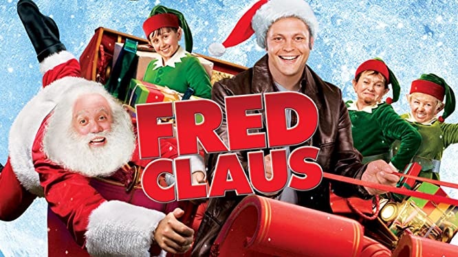 En promobild för Fred Clause-filmen där de två huvudrollerna sitter i en släde tillsammans med några nissar.