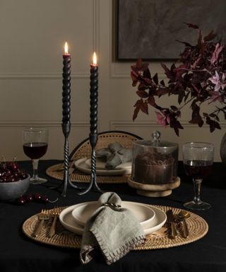 Halloween dining tablescape with black tablecloth, black dinner candles and dark red foliage