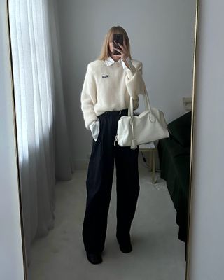 Jeanette Madsen in a white sweater and wide leg trousers.