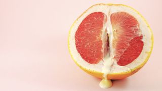 grapefruit with liquid on pink background