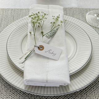 white Christmas napkin neatly tucked and placed on white dinnerware with small white blossoms