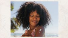 A woman on the beach applying sunscreen to her shoulder, with a blue sky and palm trees behind her