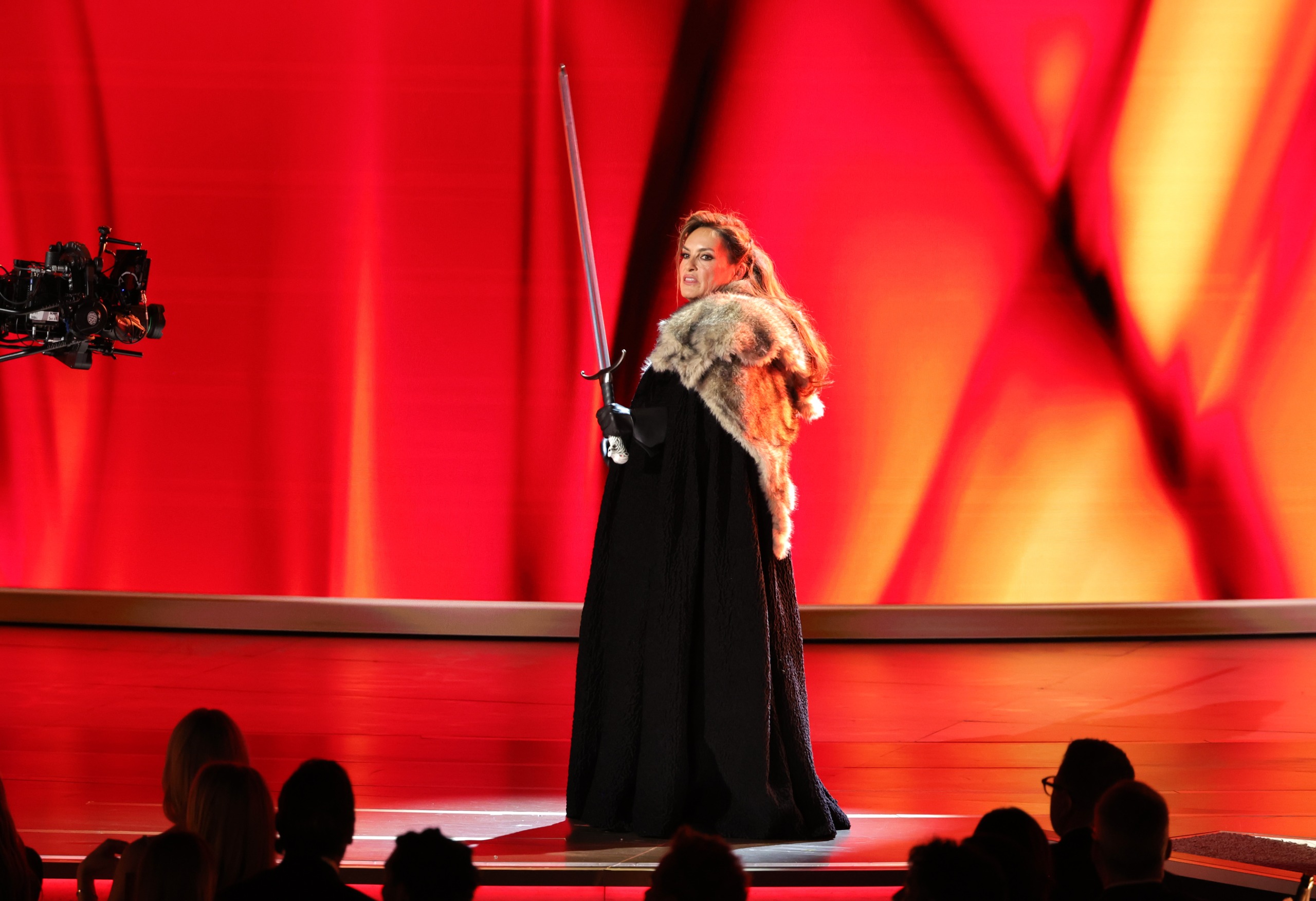 mariska hargitay wears a fur coat and cloak and wields a sword while doing a bit about game of thrones as she hosts the 2026 emmy awards