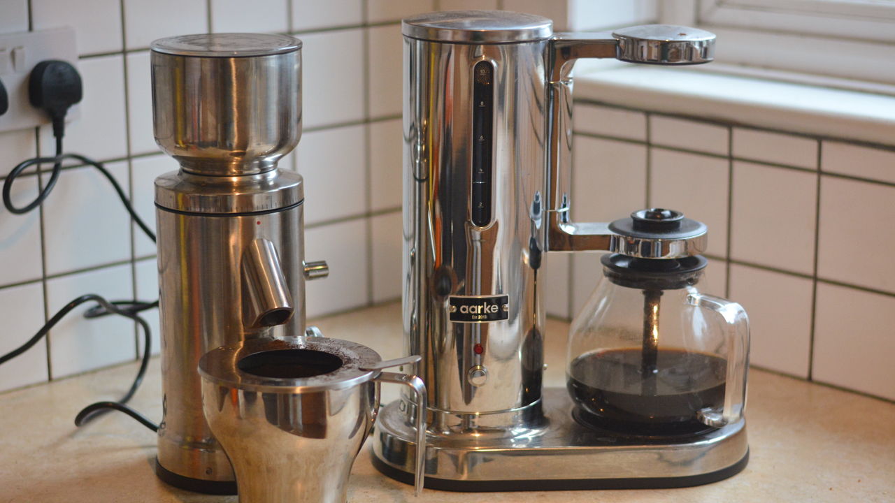 Image of the Aarke Coffee System &ndash; a stainless steel coffee bean grinder and drip coffee maker &ndash; positioned on a kitchen counter