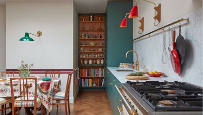 Green and white kitchen with open shelving and wooden dining table