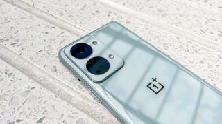 The OnePlus Nord 2T, laid face down on a stone bench