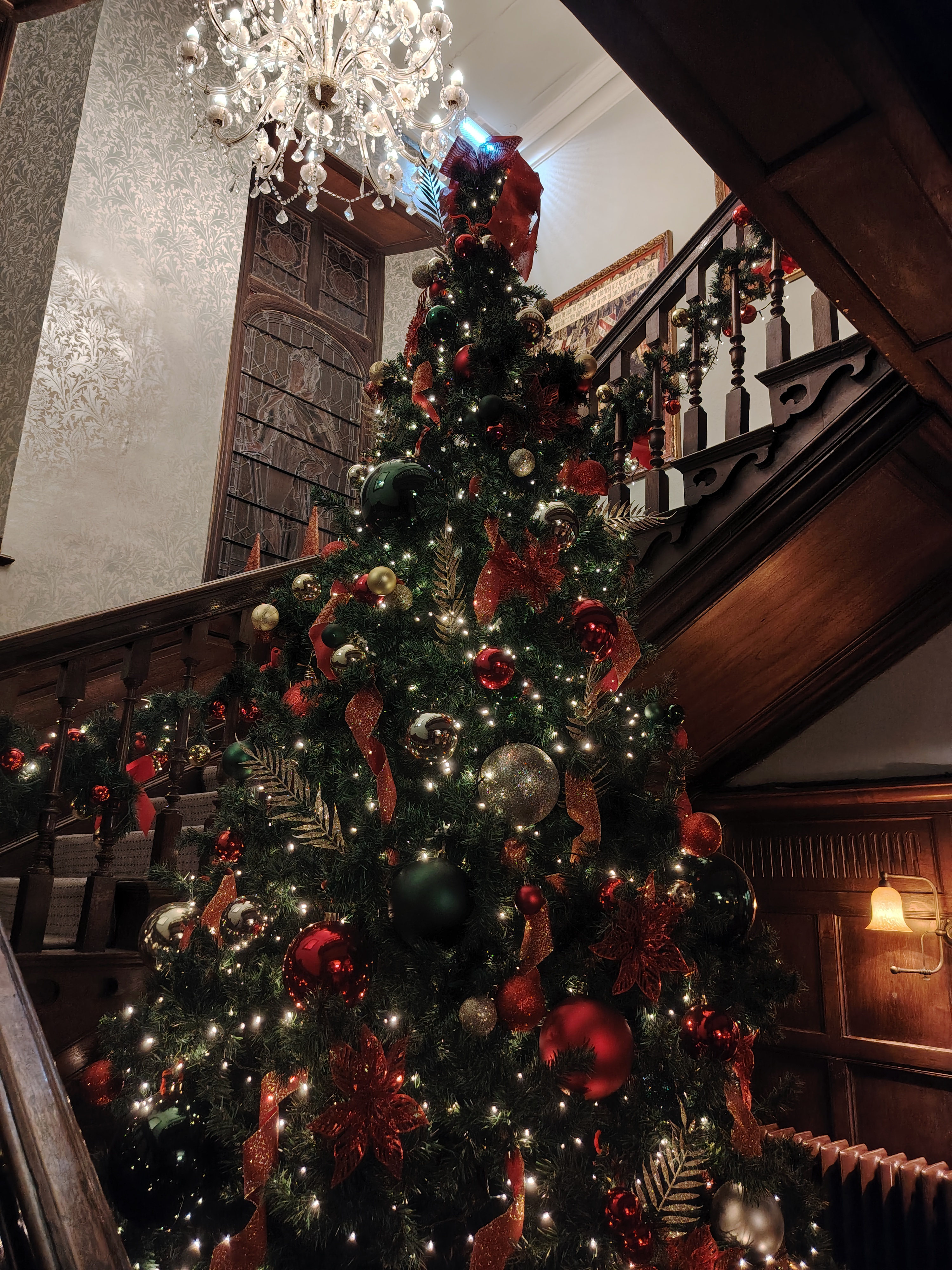 Christmas tree in front of ornate wooden stairs