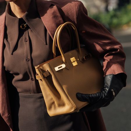 a woman carrying an hermes bag at paris fashion week