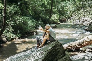 Couple taking selfie on sitting on a rock in a river