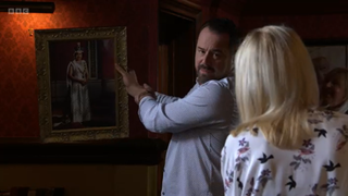 Mick Carter holds up a portrait of The Queen to Kathy Beale