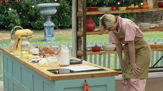 Jodie Whittaker with her head bent down stands at her work bench in The Great Celebrity Bake Off for Stand Up to Cancer