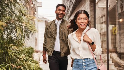 A woman and a man walking down the street, both wearing the best cheap smartwatch