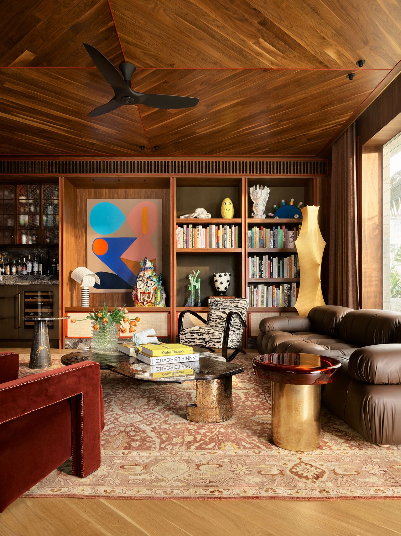 living room with timber ceiling, bookcase, akari lamp, sofa, gold coffee table, and patterned rug