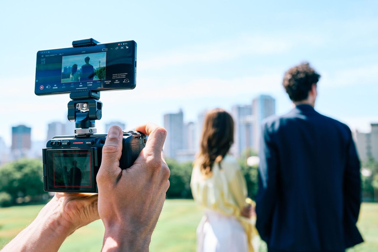Smartphone attached to Sony cine camera and displaying Sony Monitor &amp; Control app with human subjects in the frame