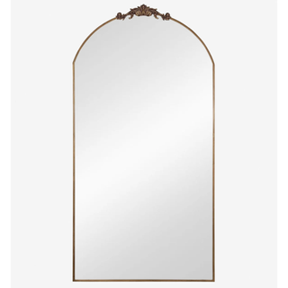 arched floor mirror with intricate gold detailing at the top