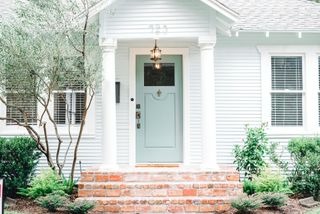 green door in white house with porch lighting