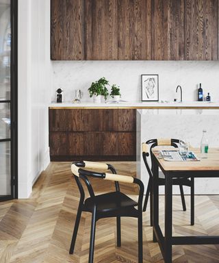 A dark wood kitchen with light wood floors and a black wood dining chair