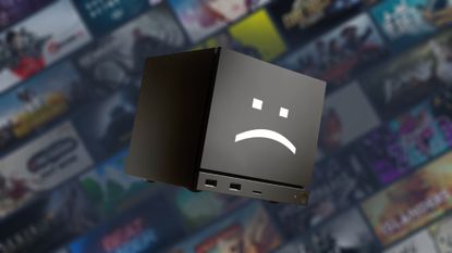 Steam Machine tilted downwards with white sad text face on front with blurred Steam game artwork in backdrop.
