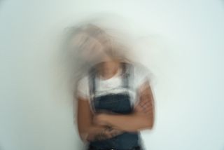 Blurred Motion Of Stressed young Woman Against Wall - highly sensitive person