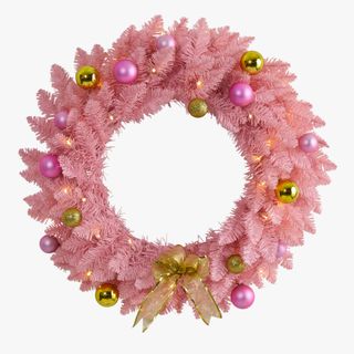Pink faux wreath hung above a mantel with berry sprigs 