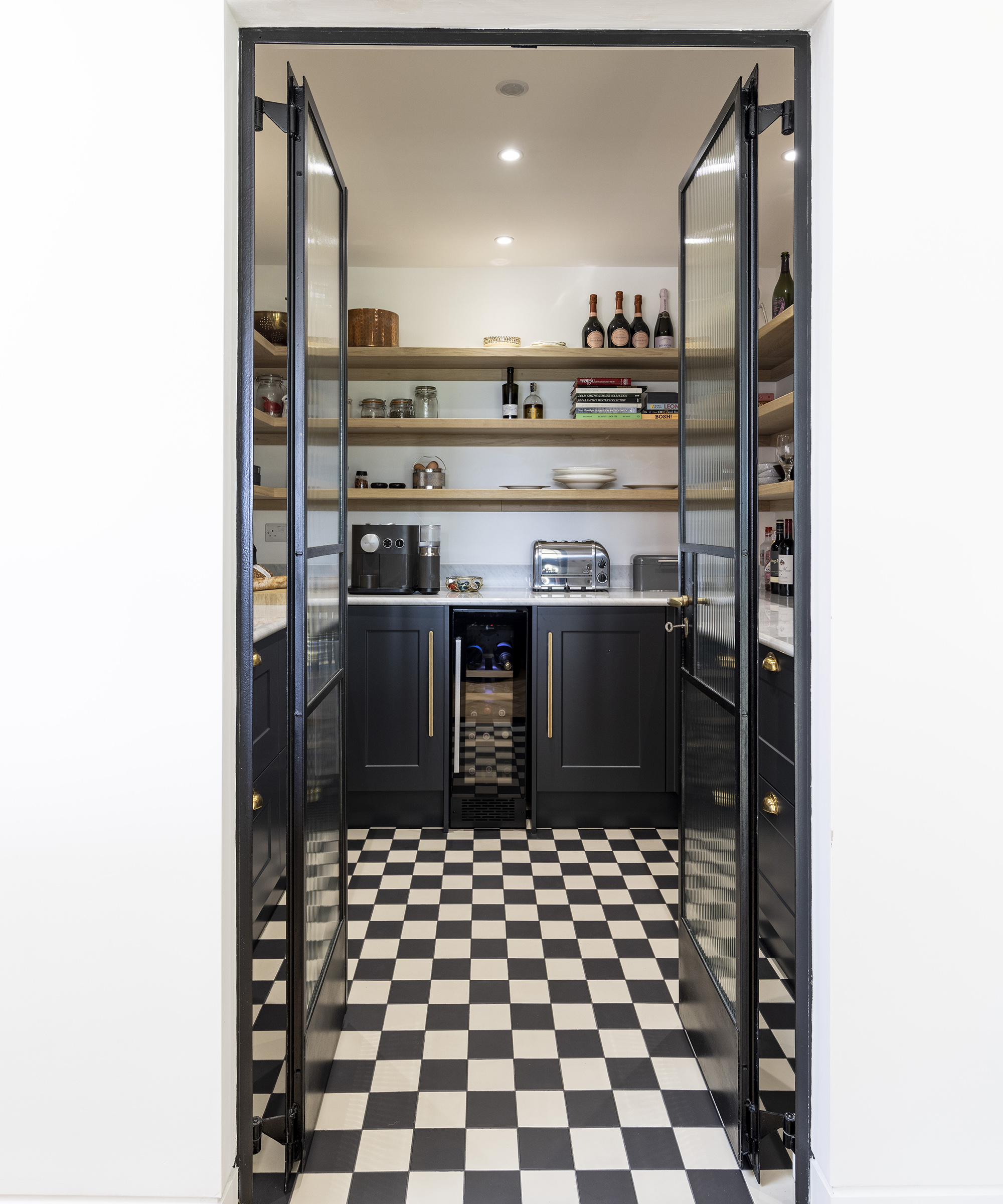 View of a kitchen utility room and pantry with black and white checked flooring