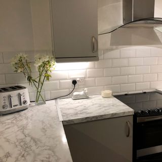 kitchen with white brick design tiles wall and ceramic kitchen countertop with grey kitchen cabinets
