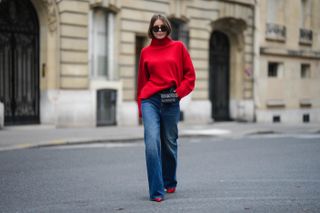 woman in a red turtleneck sweater, blue jeans, and red high heels