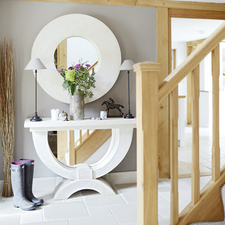 wooden stairs mirror on wall with snow boot and grey wall