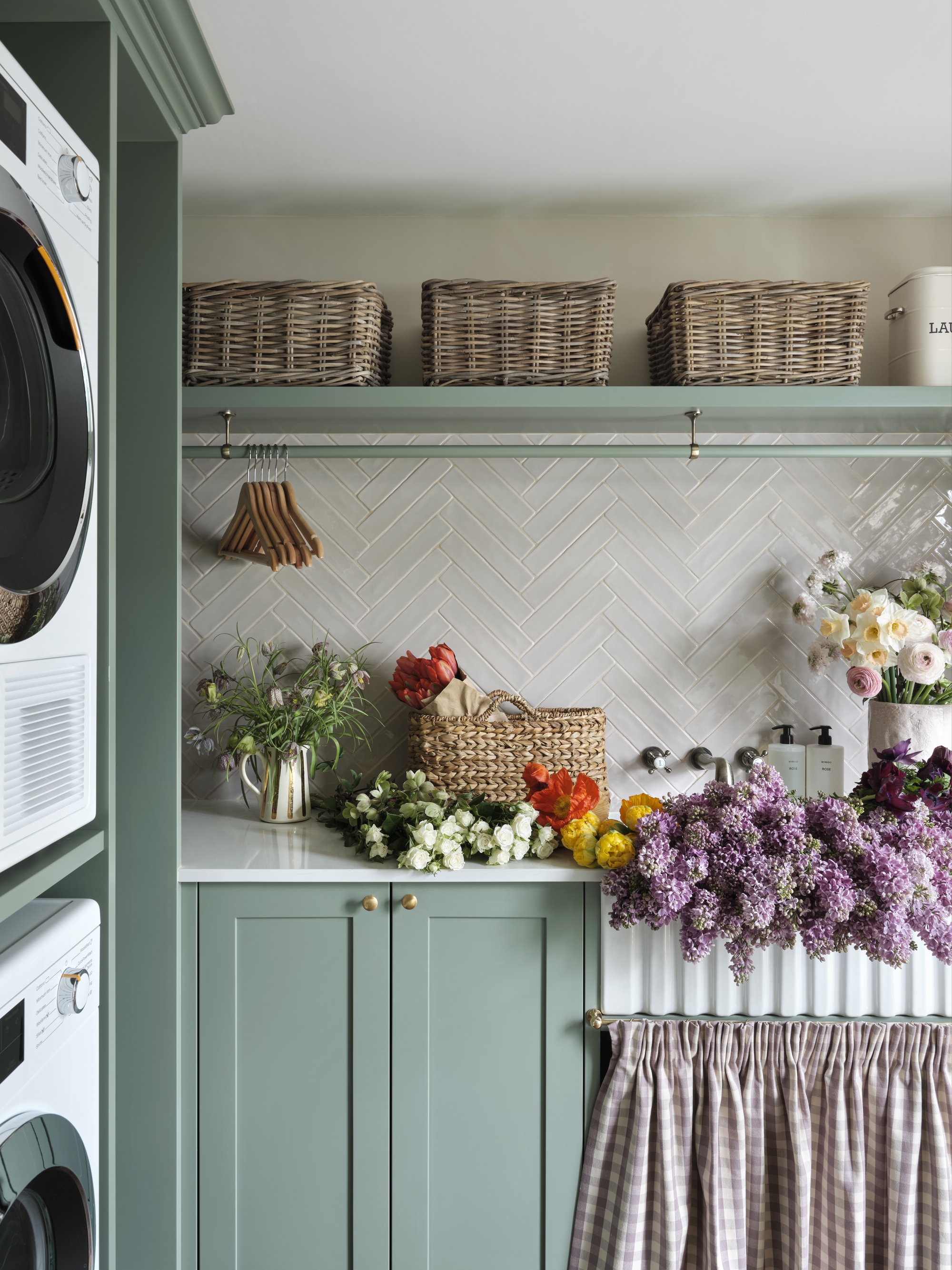 A utility room with blue cabinetry, a fluted butler sink and a high shelf with wicker storage baskets