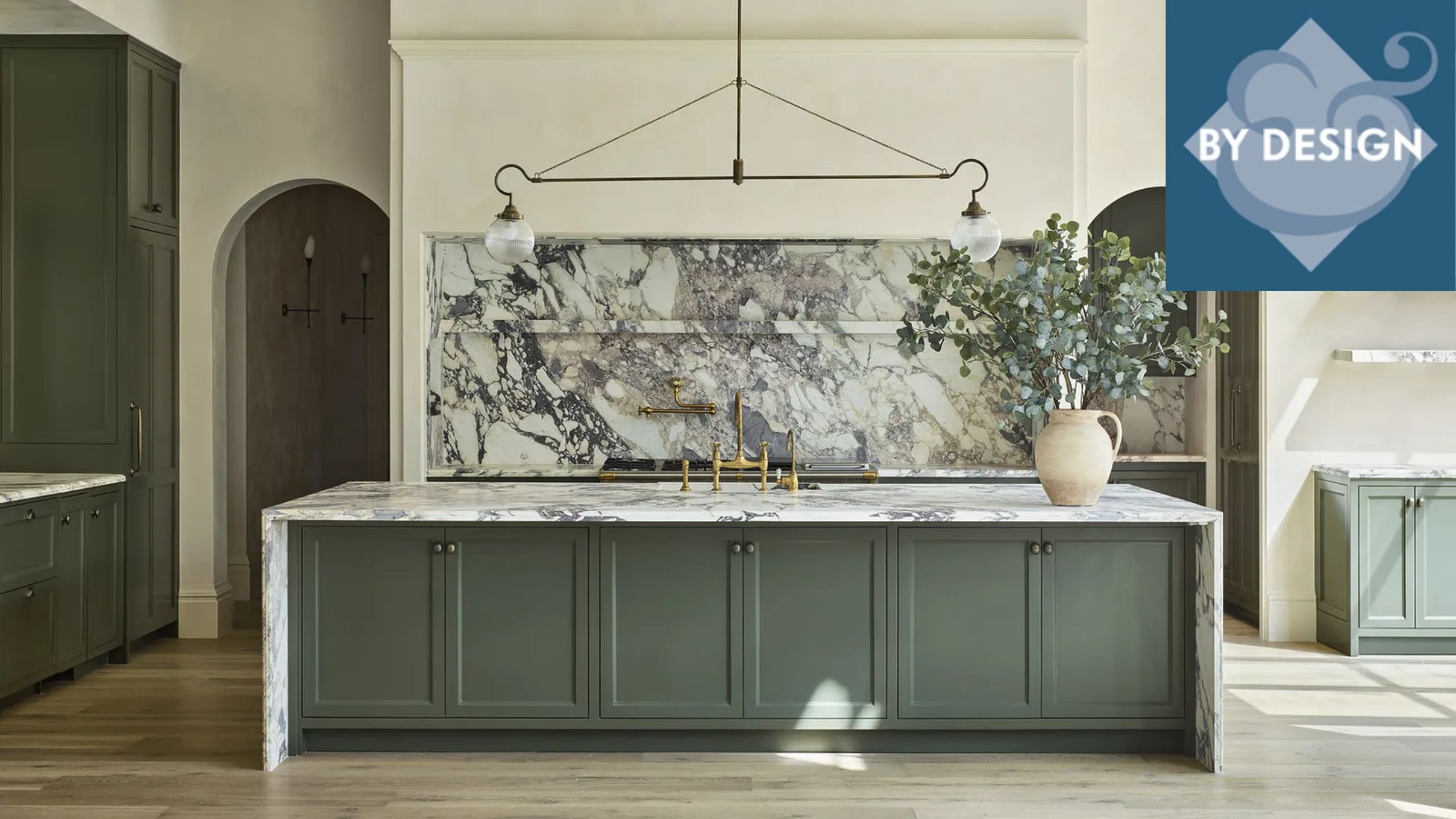 Large modern kitchen with blue-green painted cabinets, large kitchen island with marble countertop. Large marble splashback, hanging pendant light over island