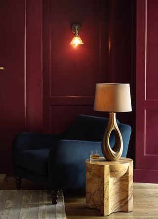 Red living room with bronze wall light and an oval sculptural side table lamp