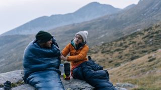 A couple in bivy sacks on a mountain