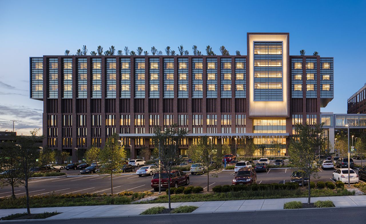 The Joint and Spine centre at dusk, lit from the inside and featuring shrubs planted on the roof