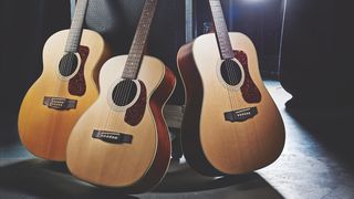 Best acoustic guitars: Three guitars together in a dark room