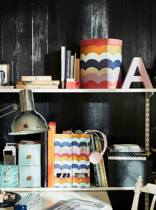 A home office with shiplap walls decorated with black wall paint decor and colorful scalloped design magazine files