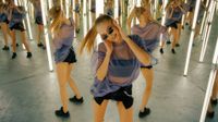 A photograph of a woman dancing in a hall of mirrors with many reflections behind her