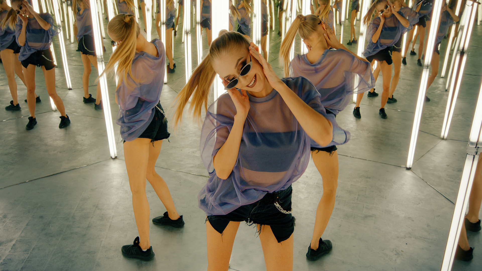 O fotografie a unei femei care dansează într-o sală de oglinzi cu multe reflexii în spate