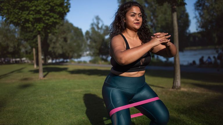 Woman squatting while using a resistance band.