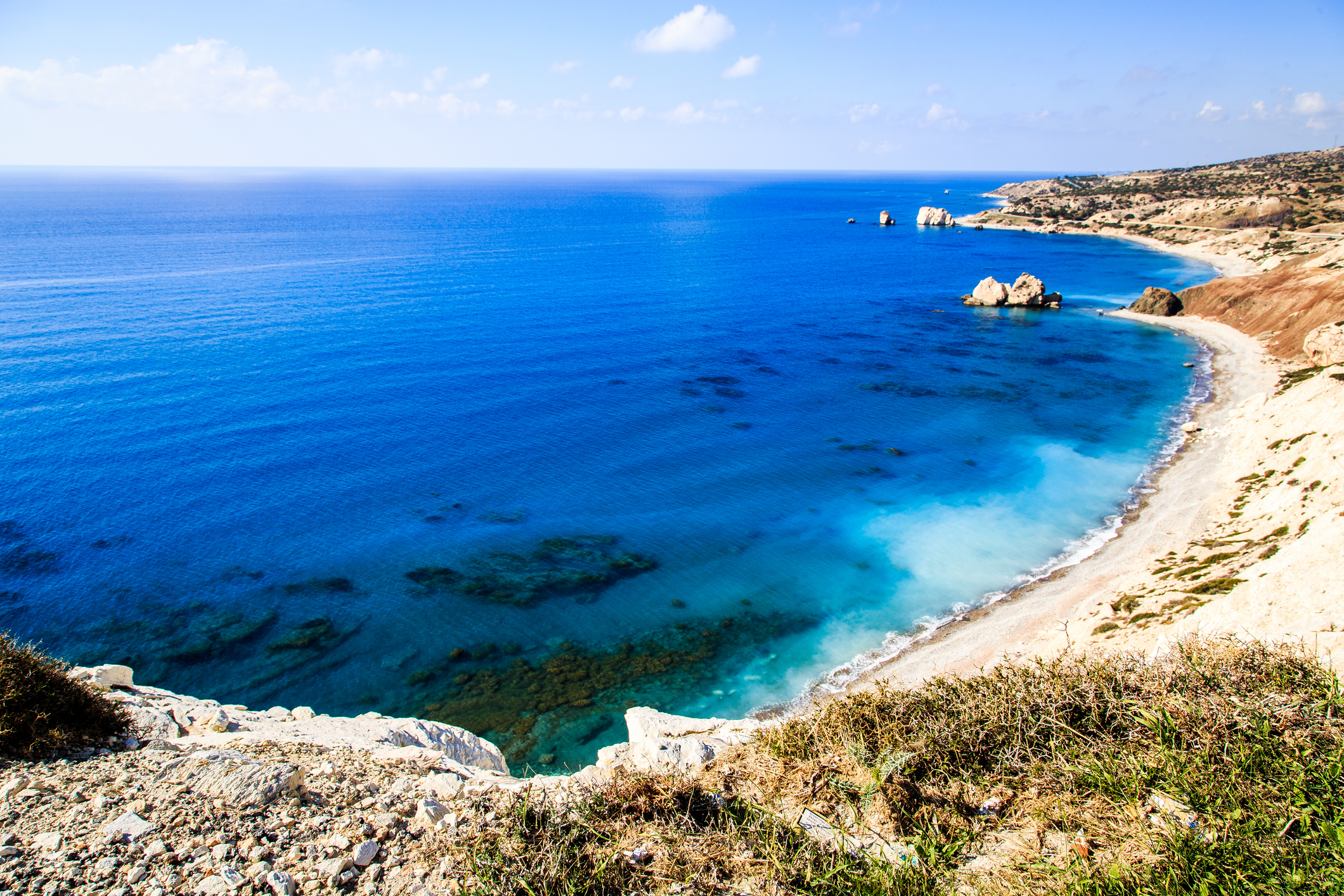 A beach in Cyprus. The water is a bright blue and the beach is deserted.