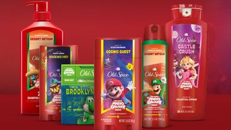 A promotional image showing a range of products from the Old Spice and The Super Mario Galaxy Movie collection. They include large body wash containers, spray bottles, and soap bars.